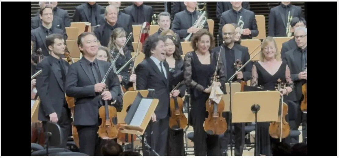 Gustavo Dudamel and the New York Philharmonic taking their bows on stage after Mahler’s Fifth, the violinists standing in the front row.